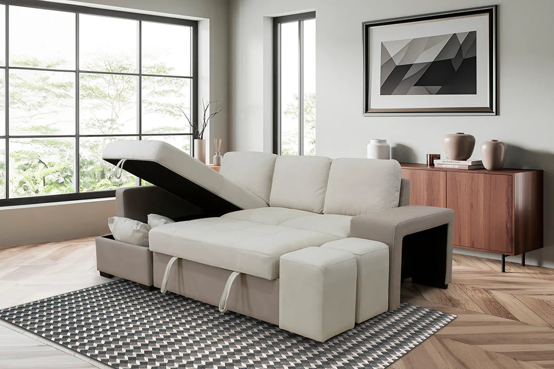 Sofá cama con chaise longue, arcón abierto y dos puffs en un salón